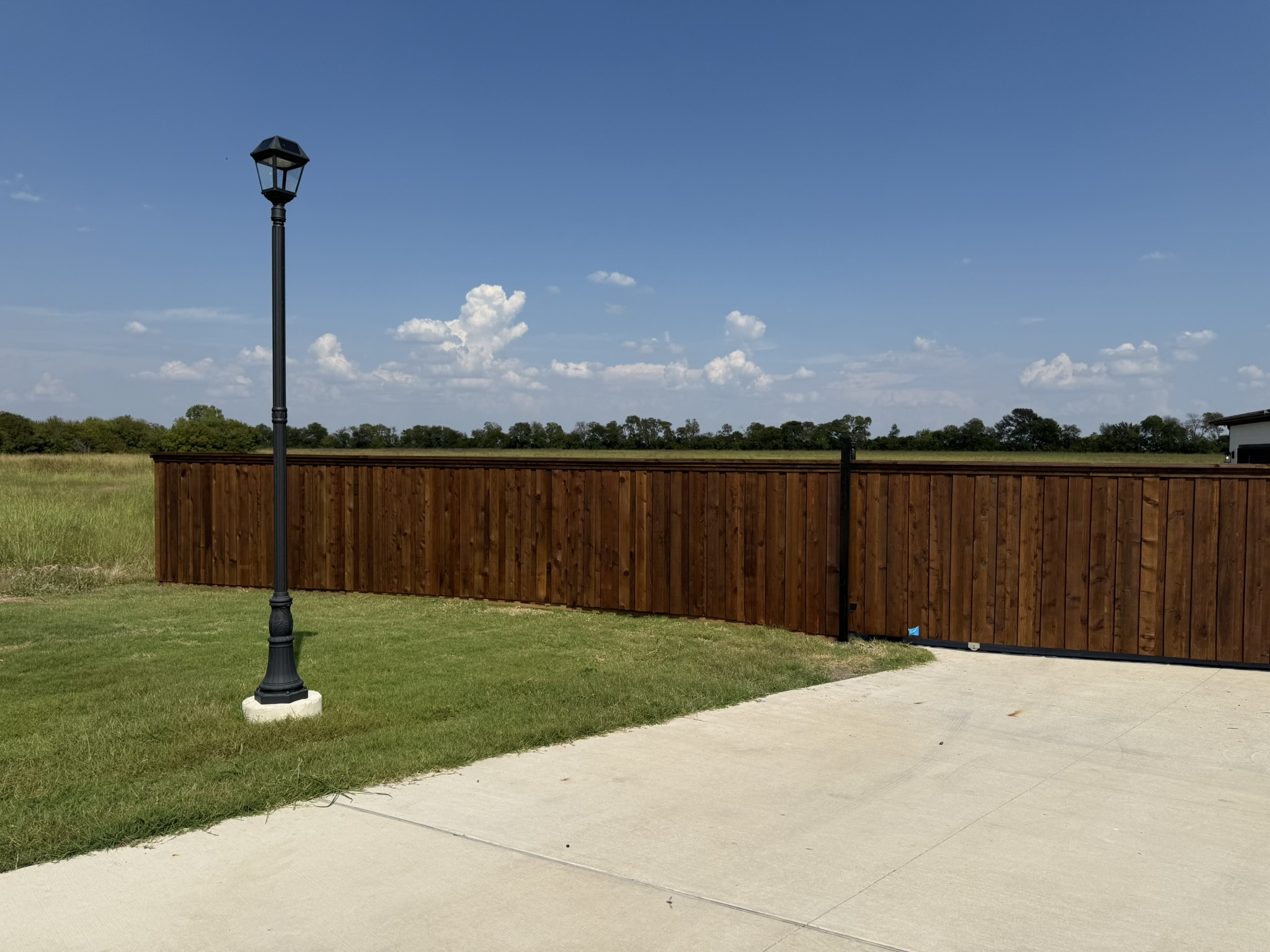 Stained cedar board-on-board privacy fence with cap rail in suburban backyard