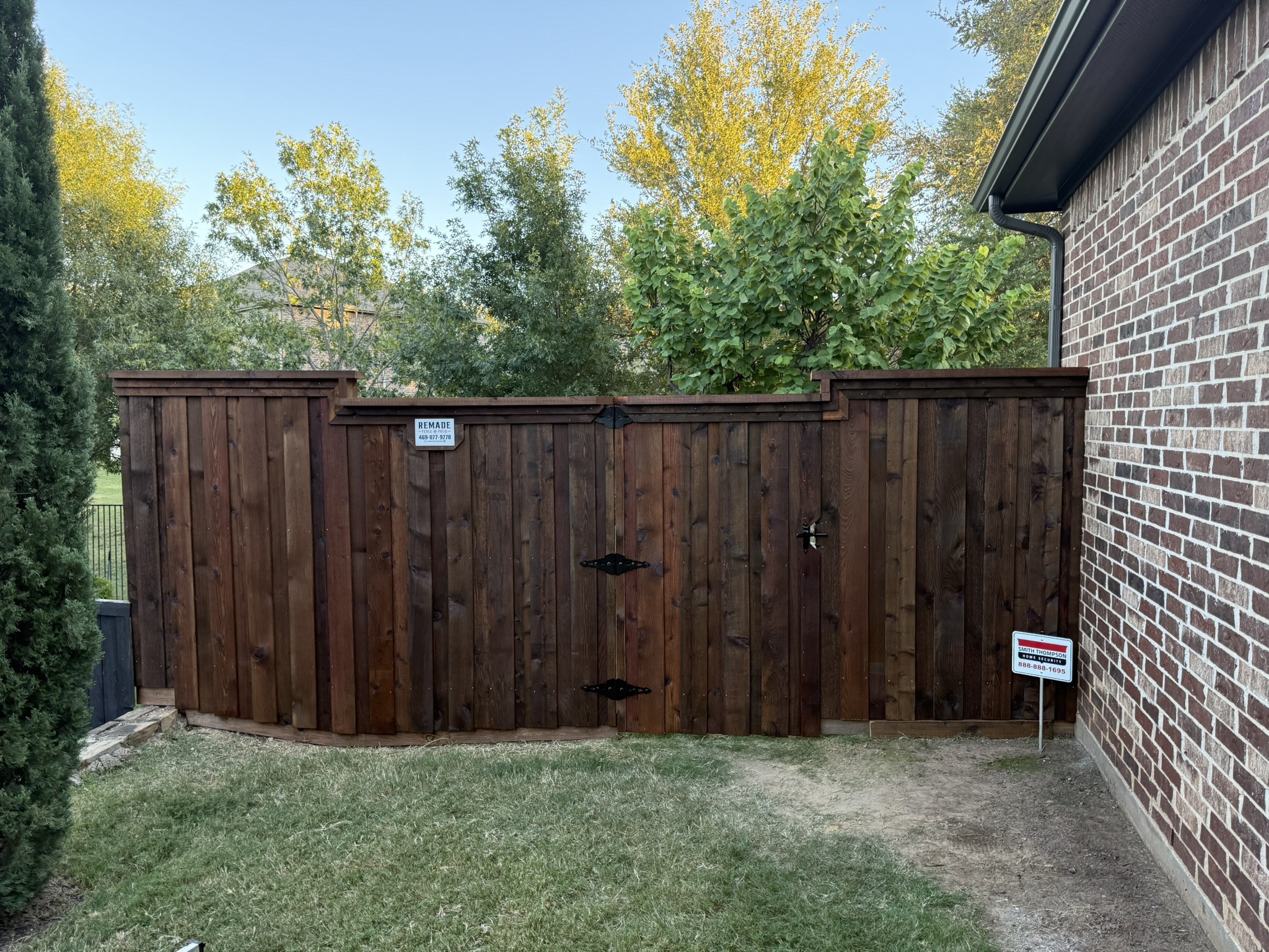 Stained cedar board-on-board fence with cap rail stepping down slope