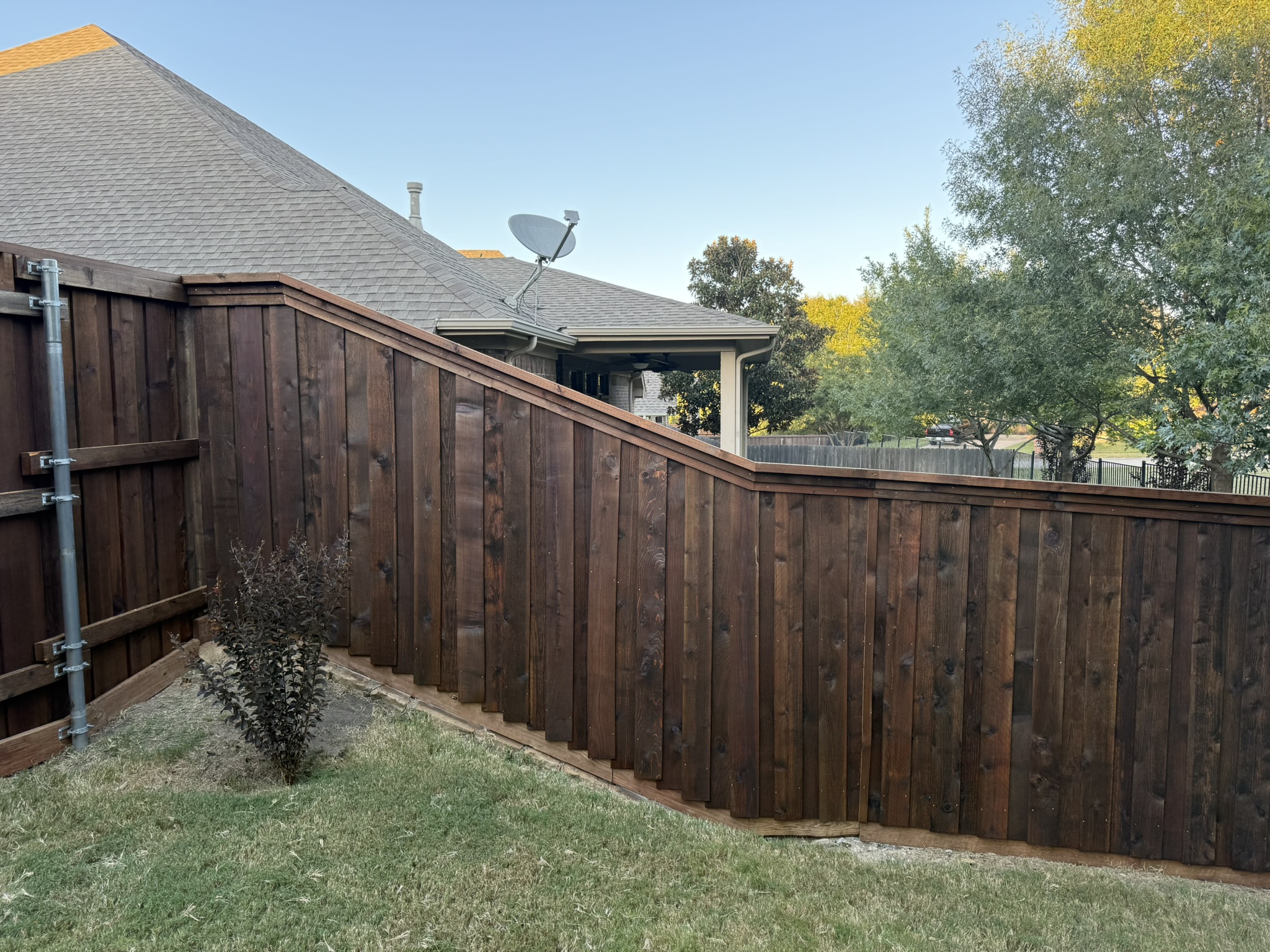 Back side of stained cedar privacy fence showing metal posts and bracing