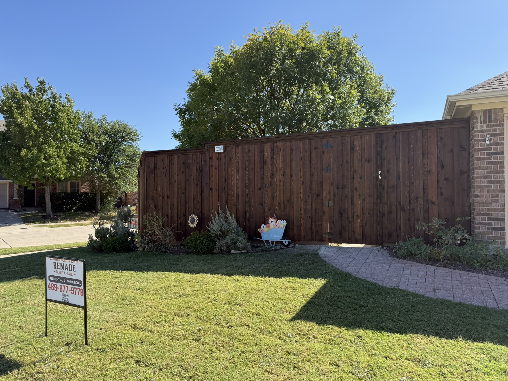 Stained cedar privacy fence with cap rail along sidewalk