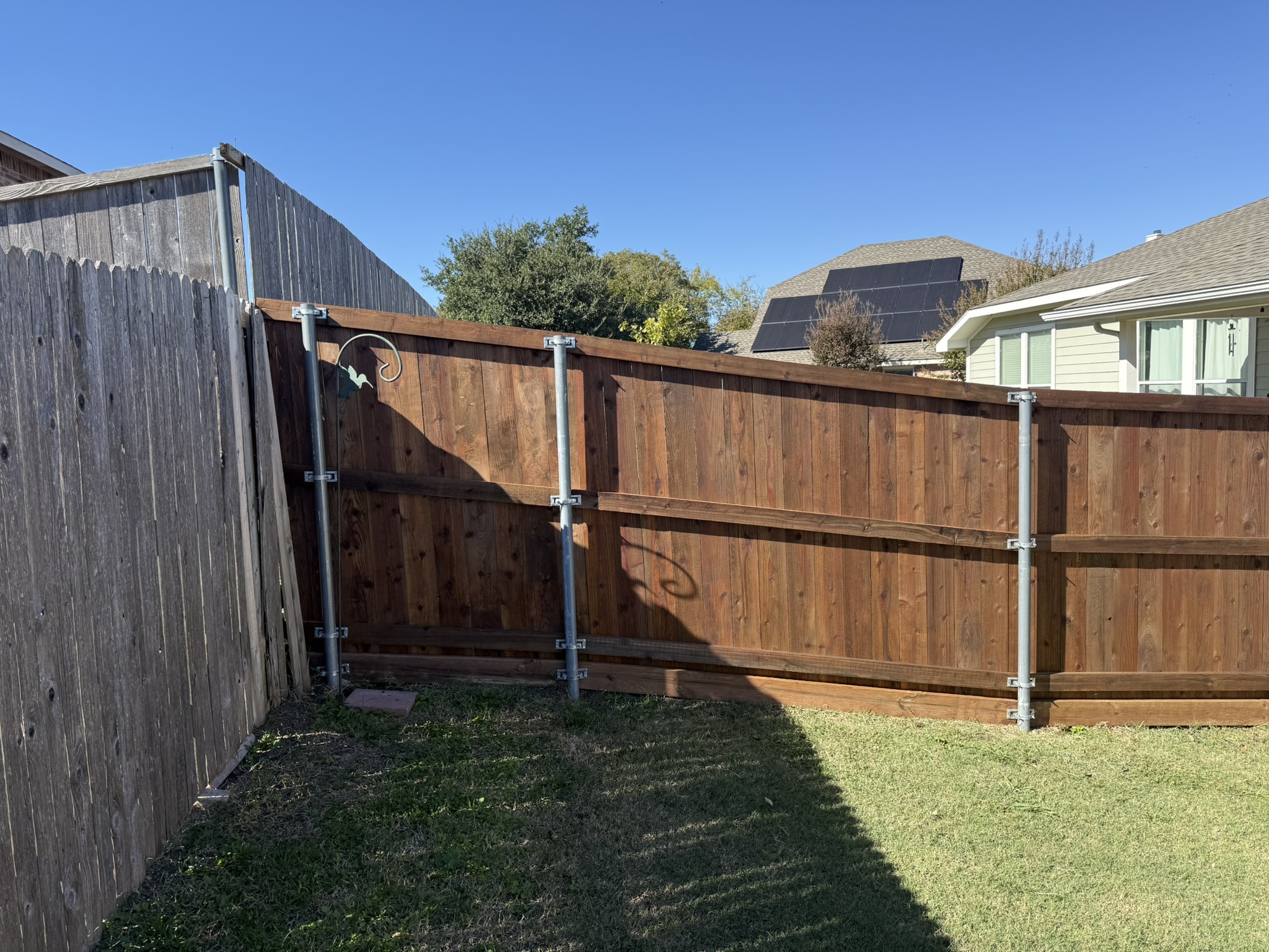 New cedar wood fence with gate and decorative iron hardware along alley