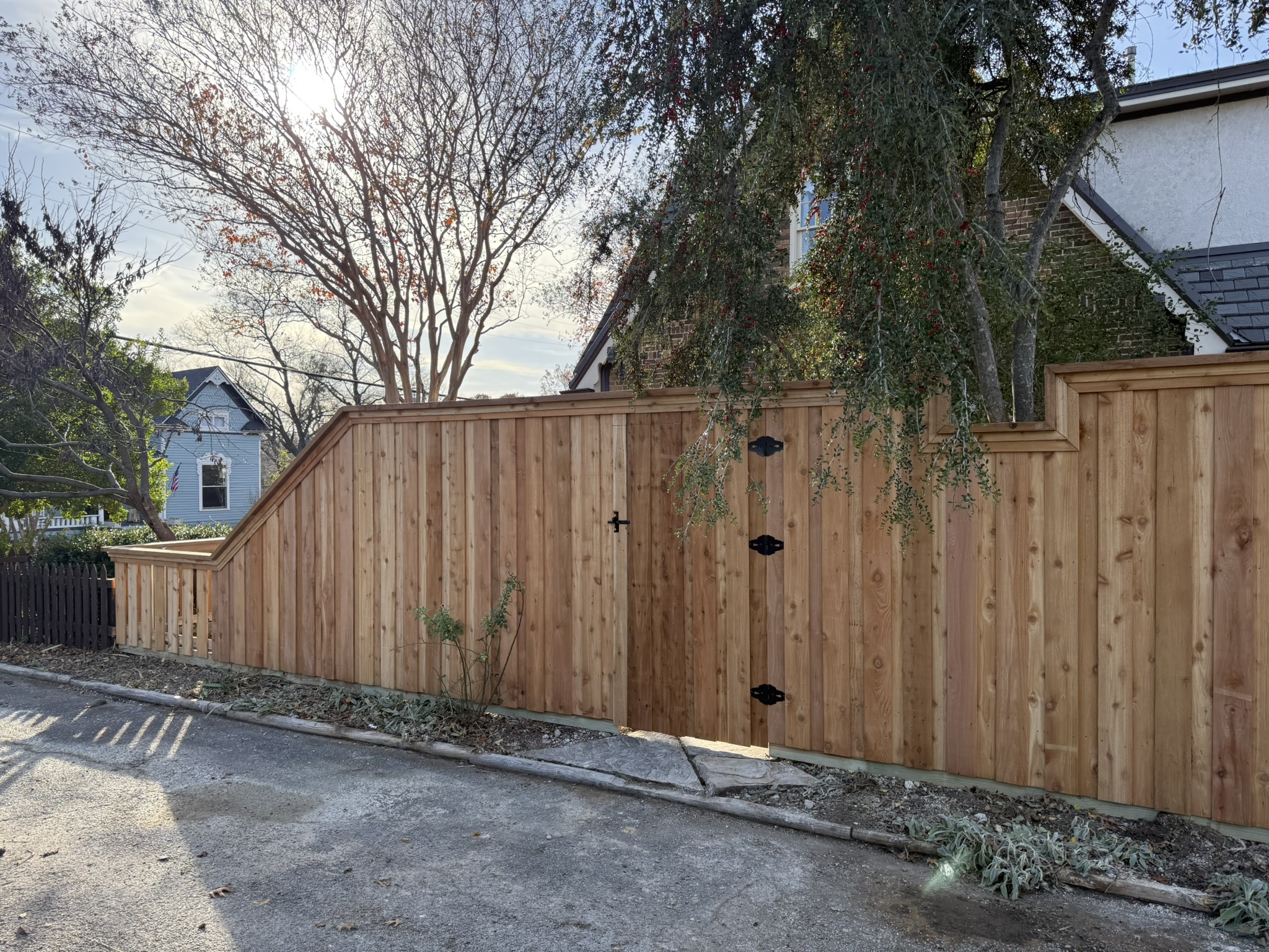 New cedar board-on-board fence with stepped height transition and decorative gate