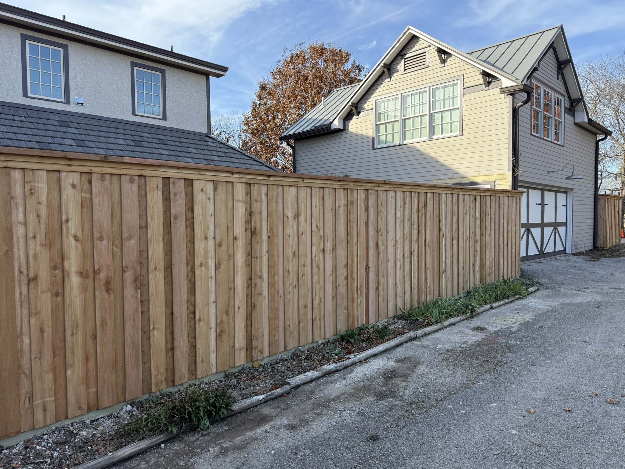 New cedar board-on-board privacy fence with metal posts alongside backyard patio