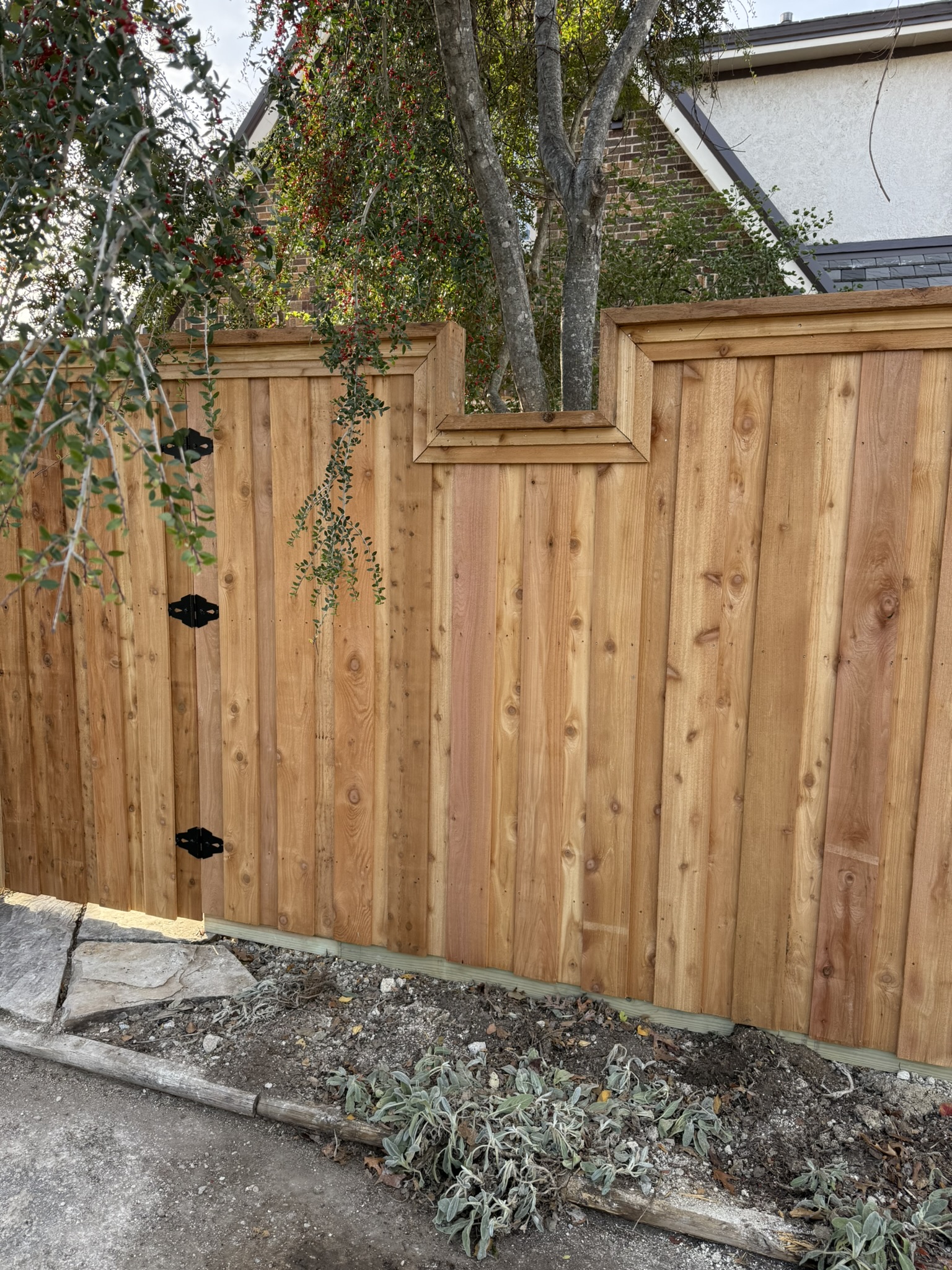 New cedar board-on-board privacy fence corner in backyard with stained wood gate