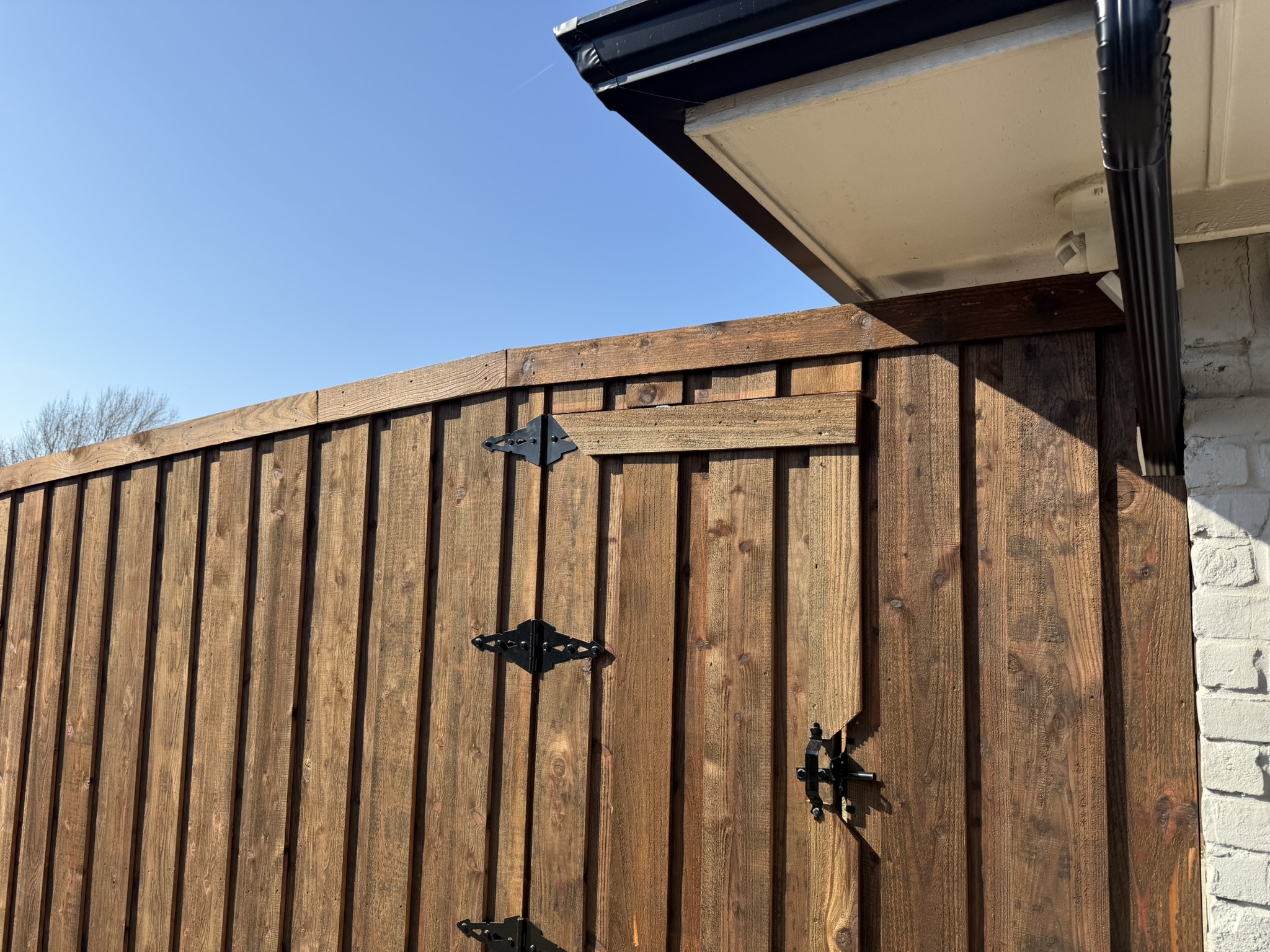 Close-up of red-stained gate beside dark-stained cedar privacy fence
