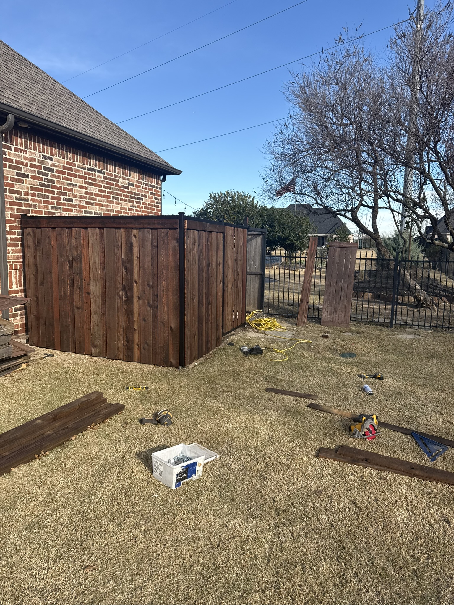 Close-up of stained cedar board-on-board gate with decorative iron hinges and latch