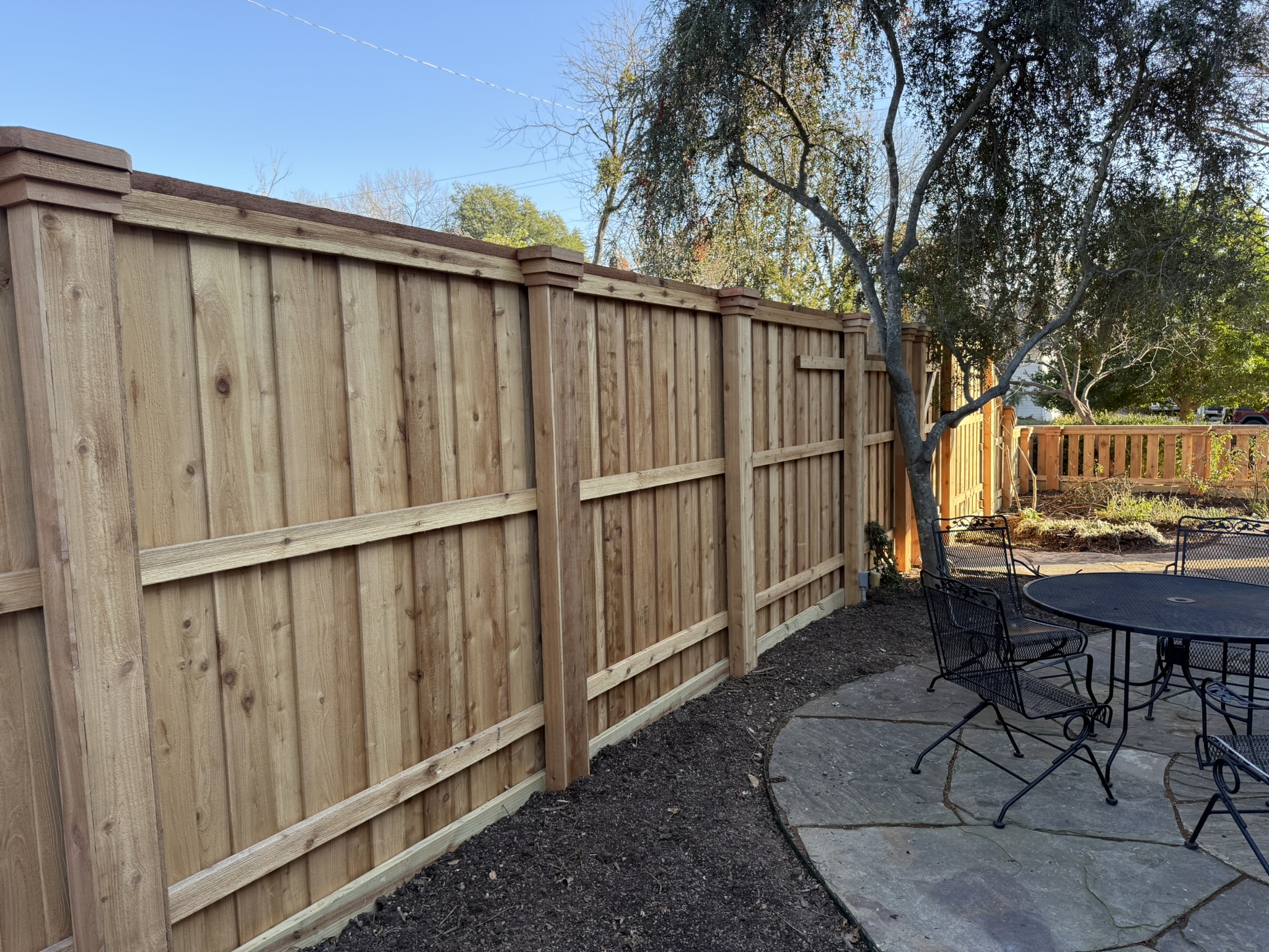 New cedar board-on-board privacy fence with cap rail near patio area
