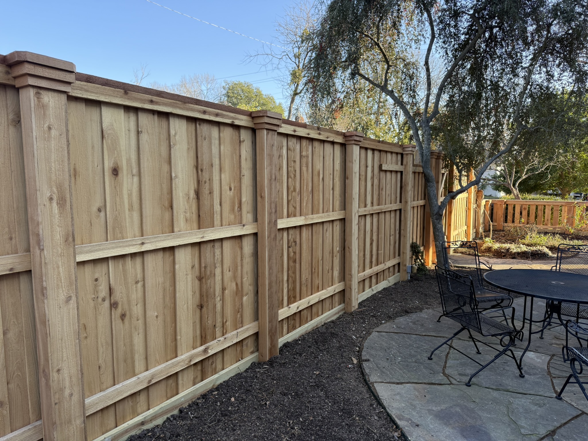New cedar board-on-board privacy fence with cap rail and decorative posts in backyard